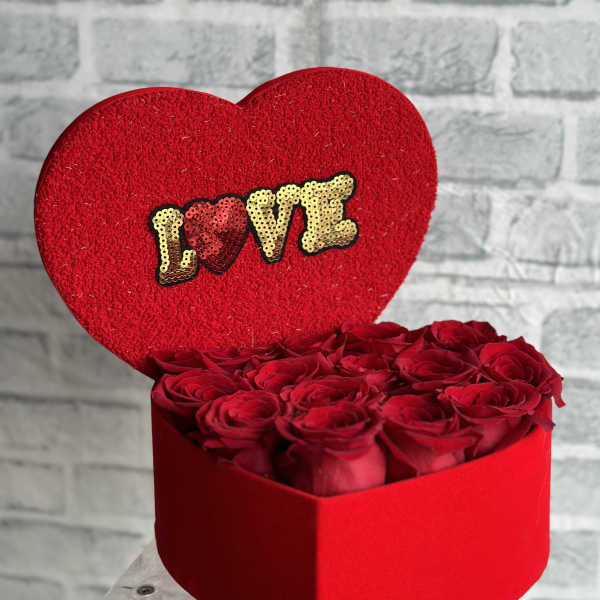 Heart-shaped box of red roses with a red LOVE topper