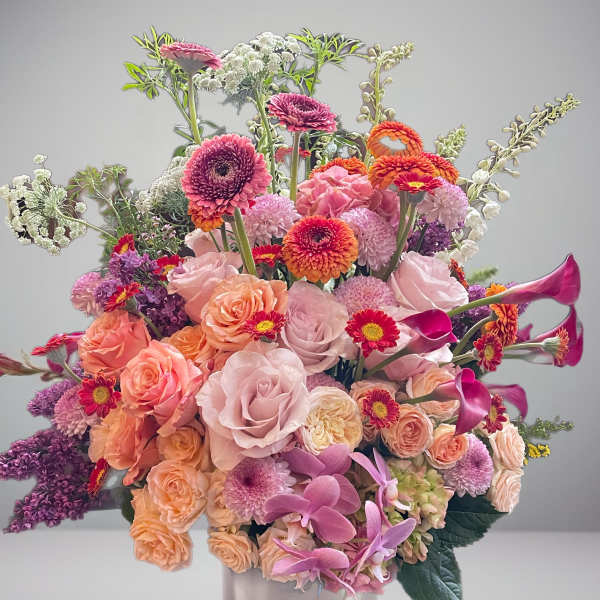 Large mixed bouquet of pink, peach, purple, and white flowers in a vase