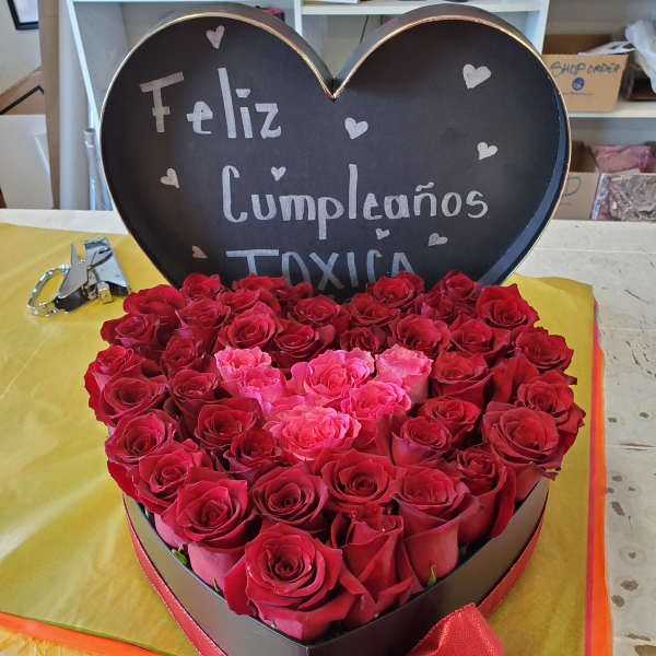 Heart-shaped box of red and pink roses with a birthday sign