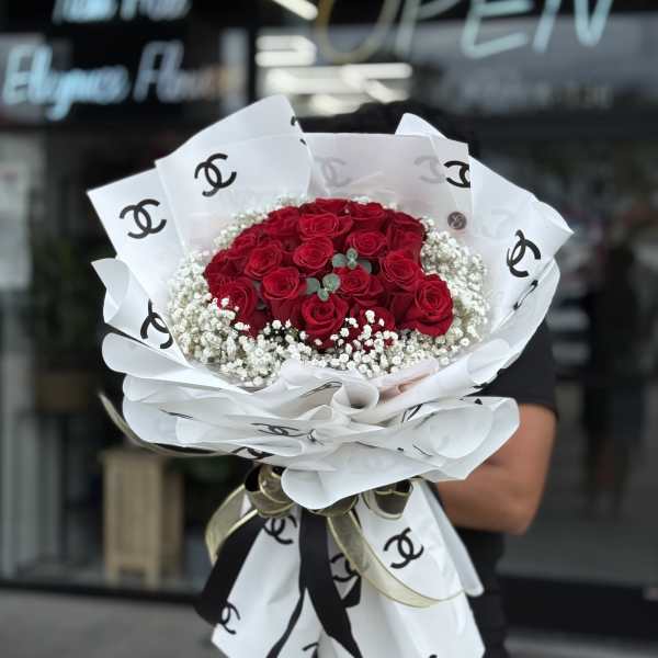 Bouquet of red roses wrapped in white paper with black logos