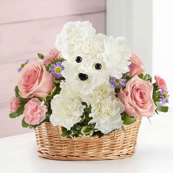 White teddy bear made of flowers in a wicker basket with pink roses
