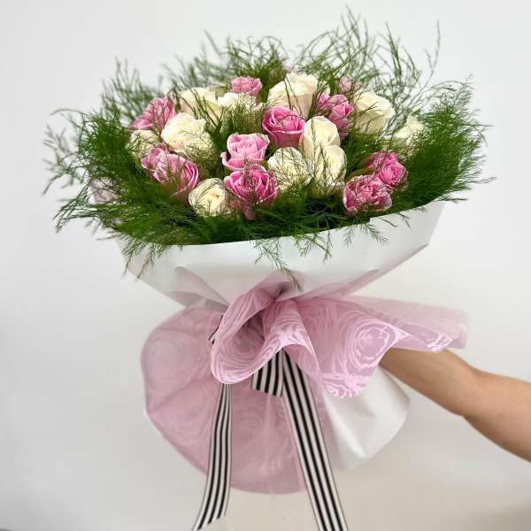 Bouquet of pink and white roses wrapped in pink paper