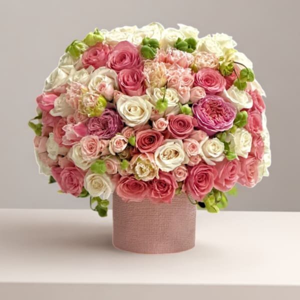 Round bouquet of pink and white roses in a pink textured box