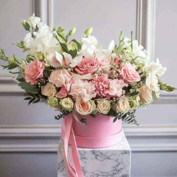 Pink and white floral arrangement in a pink hat box with ribbon