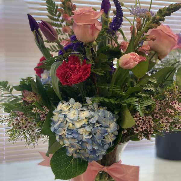 Mixed bouquet in a glass vase with pink roses and blue hydrangea