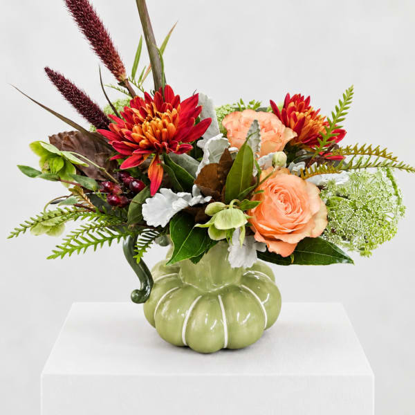 Bouquet of peach and red flowers in a green pumpkin-shaped vase