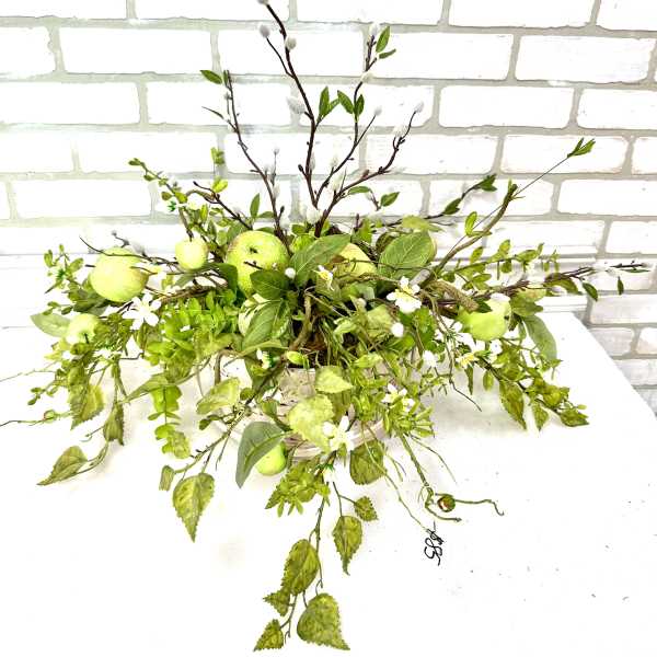 Green floral arrangement with apples in a low container