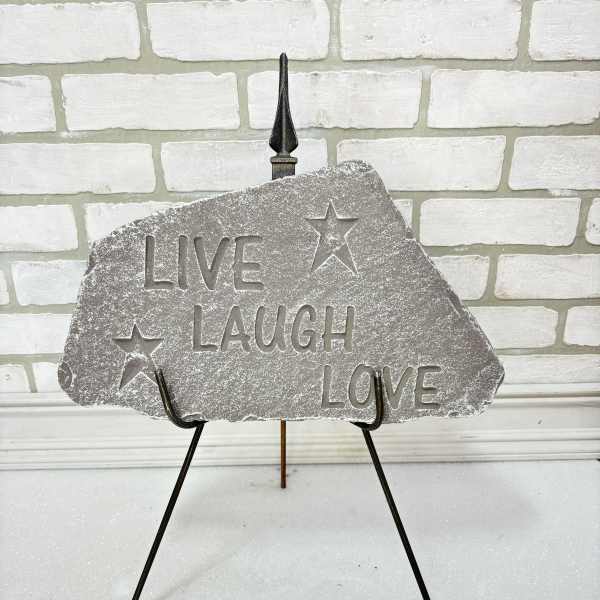 Decorative stone sign on a metal stand with the words Live Laugh Love