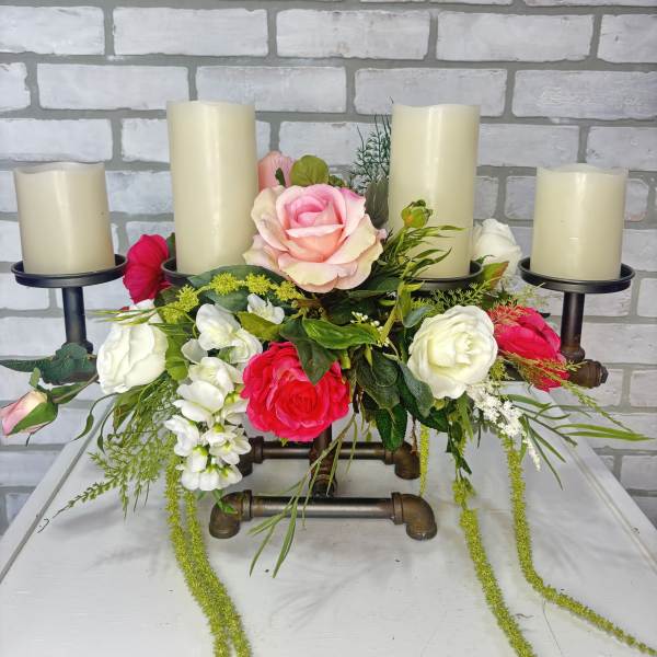 Floral centerpiece with four pillar candles and pink, white, and red roses
