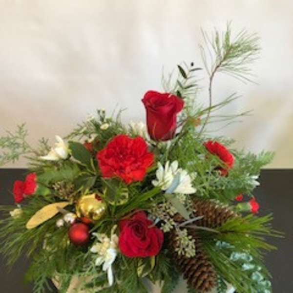 Red roses and carnations arranged with pinecones in a white container