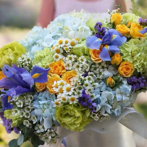 Colorful bouquet with blue hydrangeas, yellow roses, and purple irises