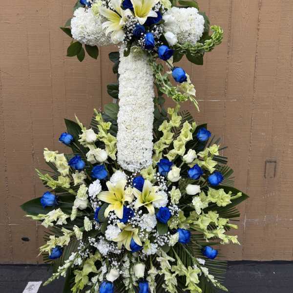 Large white floral cross with blue roses and yellow lilies