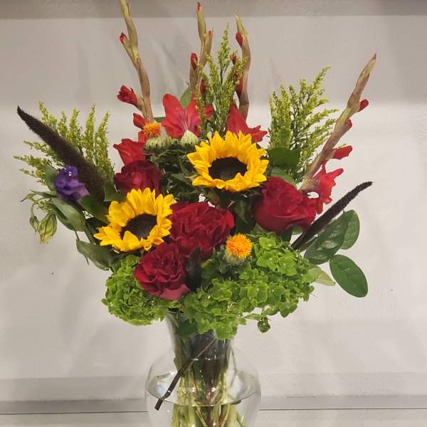 Mixed bouquet of sunflowers and red roses in a clear glass vase