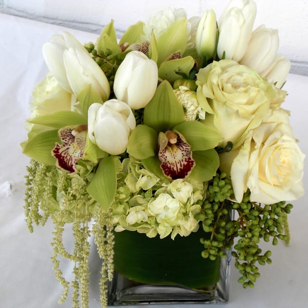 Cream and green floral arrangement in a square glass vase