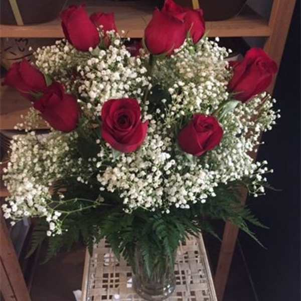 Bouquet of red roses and white baby's breath in a glass vase