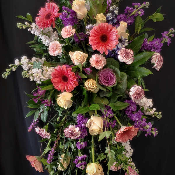 Tall floral spray with pink gerberas, cream roses, and purple blooms