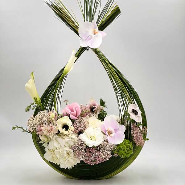 Floral arrangement in a curved green frame with pink and white blooms
