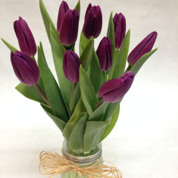 Purple tulips in a glass jar tied with raffia