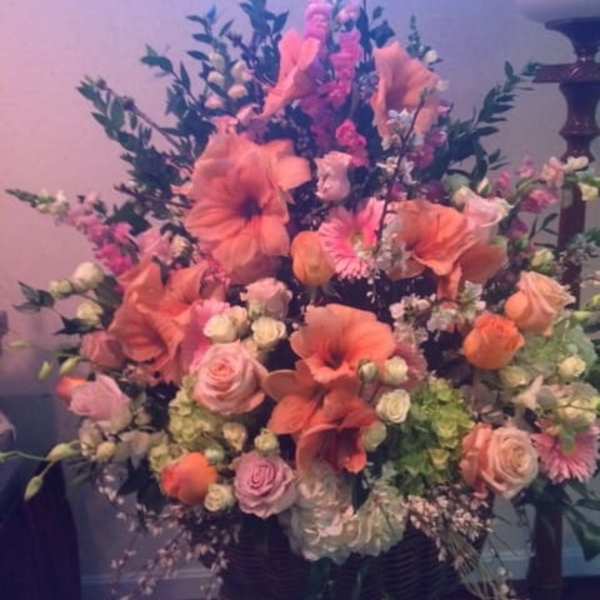 Large pink and peach floral arrangement in a dark vase