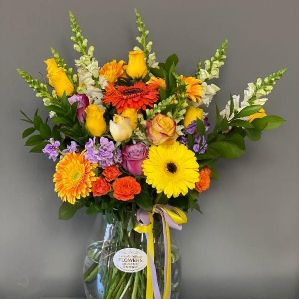 Colorful mixed bouquet in a clear glass vase with ribbon