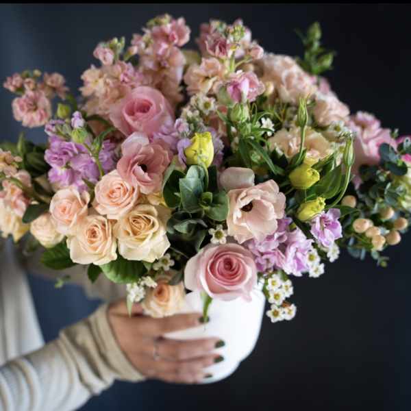 Woman holding a pastel bouquet in a white vase