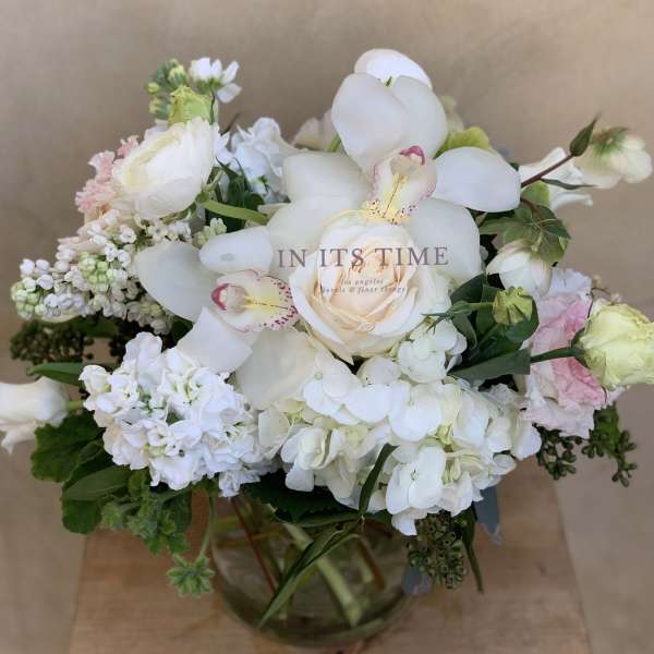 White and pale pink floral arrangement in a glass vase