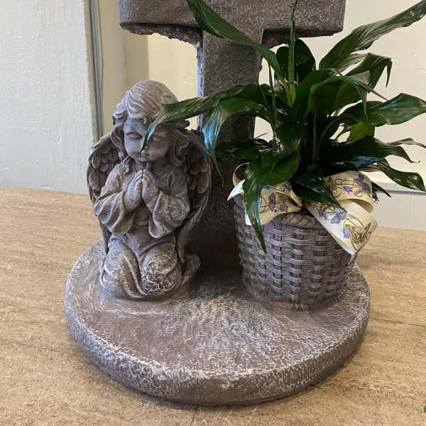 Potted green plant beside a stone cross and angel statue