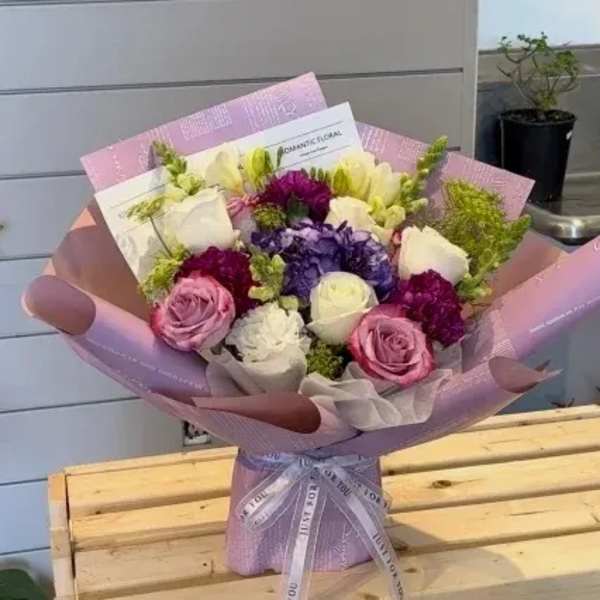 Bouquet of pink, white, and purple flowers wrapped in lavender paper