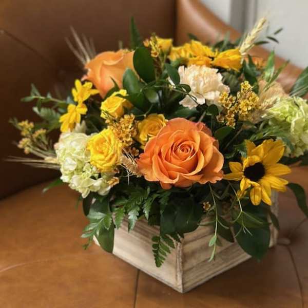Orange roses and yellow flowers arranged in a wooden box