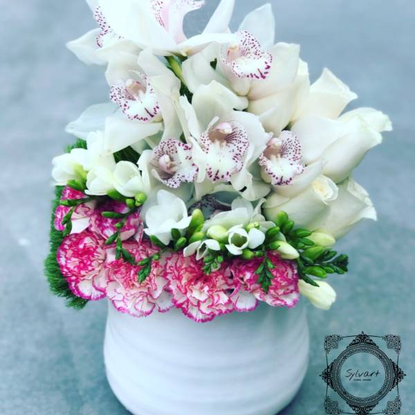 White orchids and pink carnations arranged in a white vase
