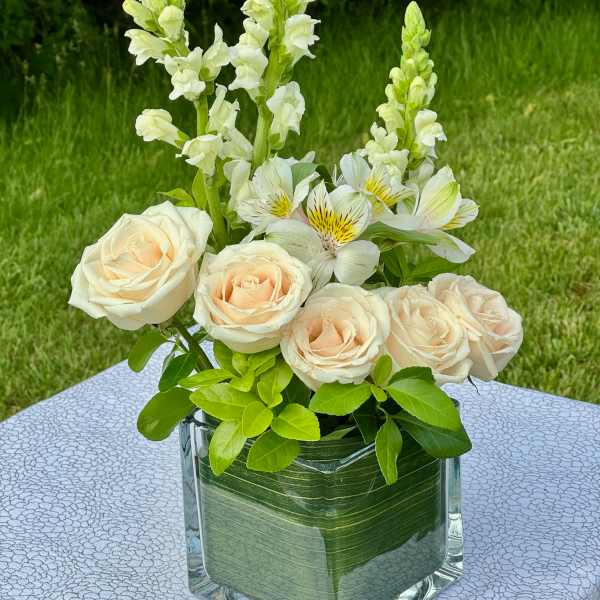 Cream roses and white snapdragons in a glass vase