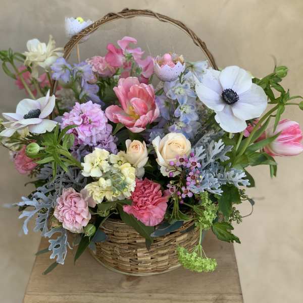 Mixed pastel flowers arranged in a wicker basket