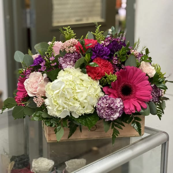 Mixed bouquet in a wooden box with pink, purple, white, and red flowers