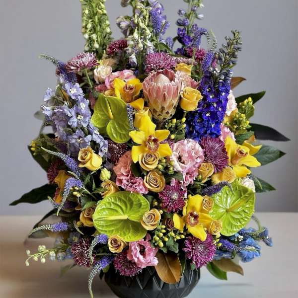 Colorful mixed bouquet in a black vase with tall purple and green spikes
