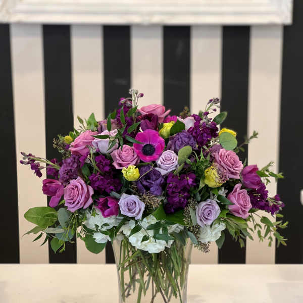 Mixed purple and pink flower arrangement in a clear glass vase