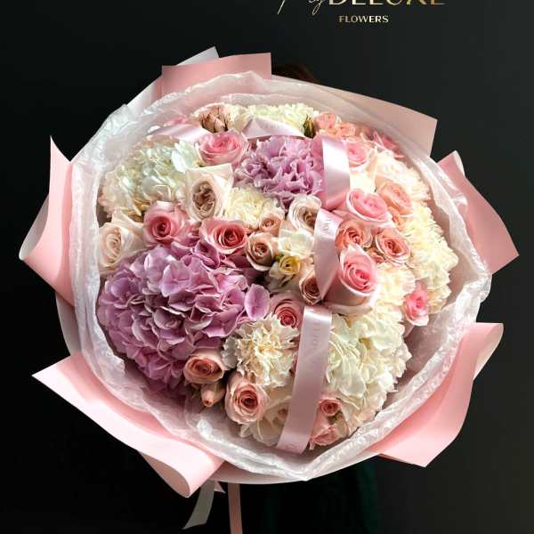 Large bouquet of pink and white roses and hydrangeas wrapped in pink paper