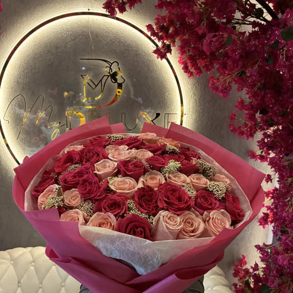 Large bouquet of pink and blush roses wrapped in bright pink paper