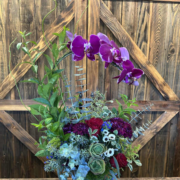 Purple orchids and mixed flowers in a blue vase