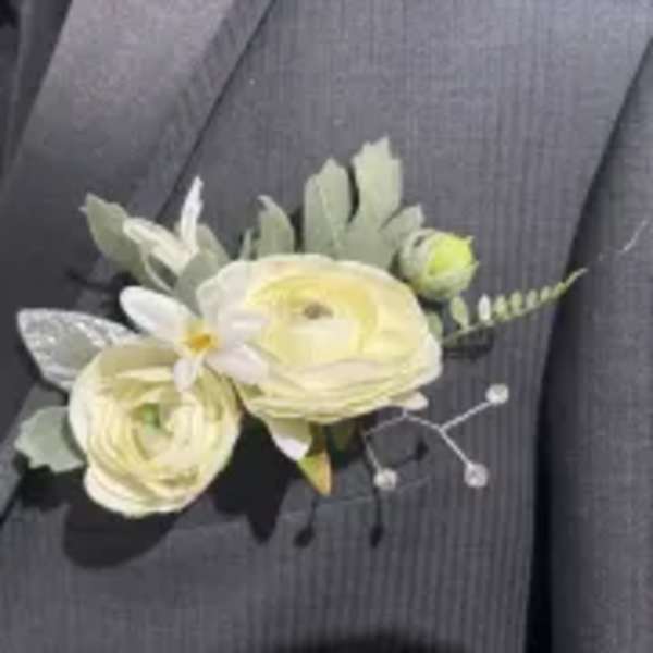 White floral boutonniere pinned to a dark suit jacket