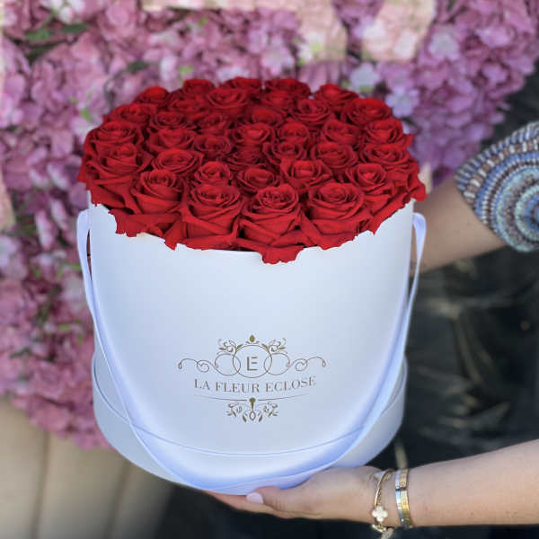 Red roses arranged in a white round hat box