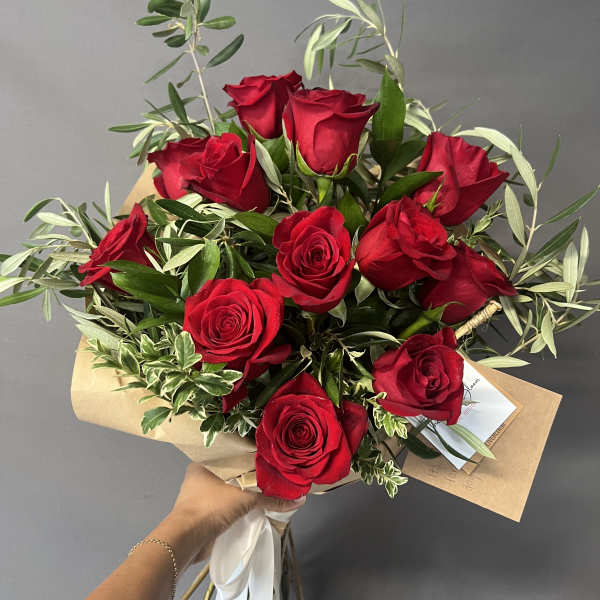 Bouquet of red roses with mixed greenery wrapped in kraft paper