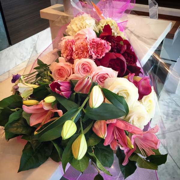 Mixed bouquet of pink, white, and red flowers wrapped in pink mesh