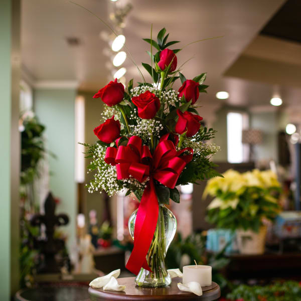 Red roses arranged in a clear glass vase with a red ribbon