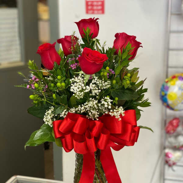 Red roses in a clear glass vase with a large red ribbon