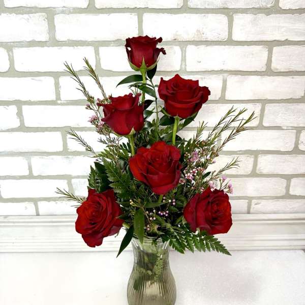 Red roses arranged in a clear glass vase