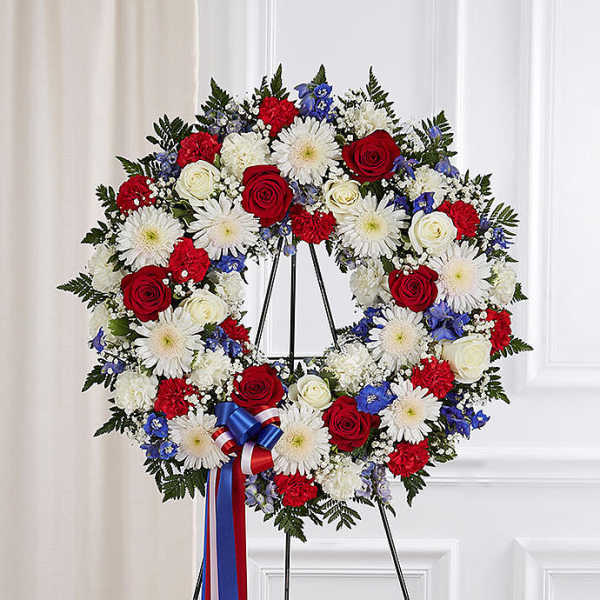 Circular wreath of red, white, and blue flowers on a stand