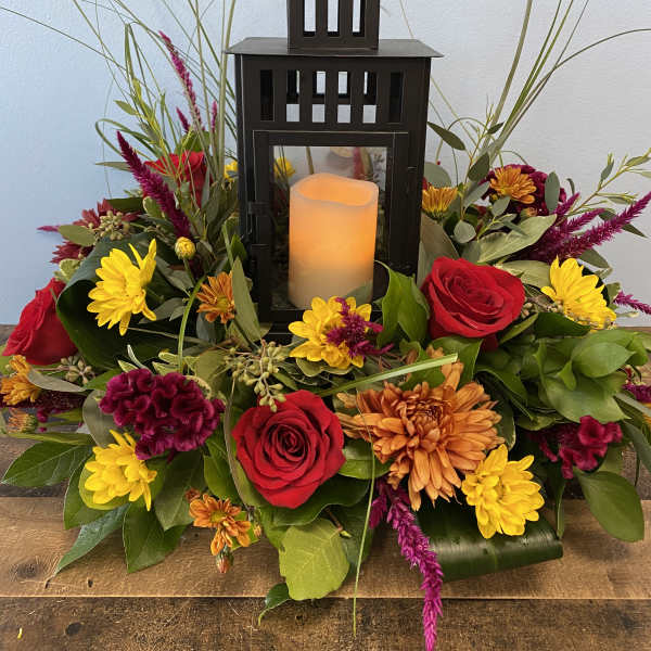 Floral arrangement with a black lantern and candle in the center
