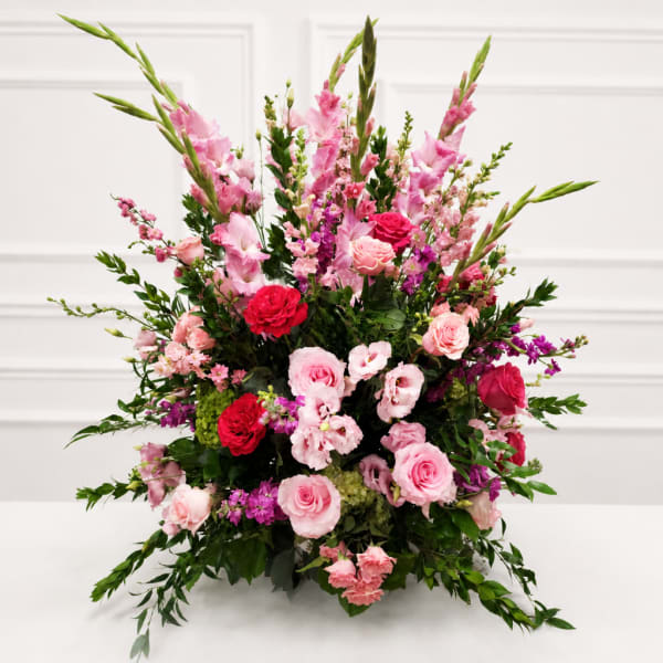 Large pink and red floral arrangement with roses and tall spikes