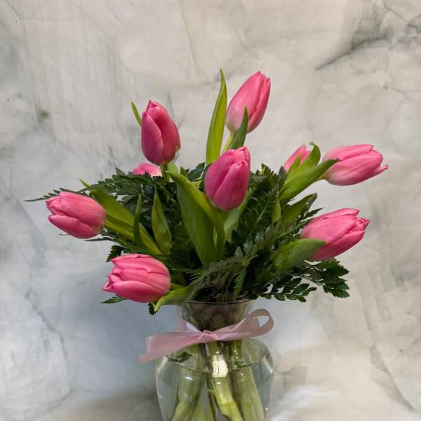 Pink tulip bouquet in a clear glass vase with a pink ribbon
