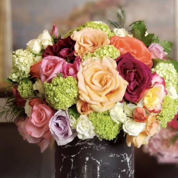 Mixed bouquet of roses and green hydrangeas in a black vase